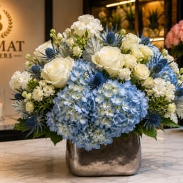 Blue hydrangeas and white roses arranged in a silver vase