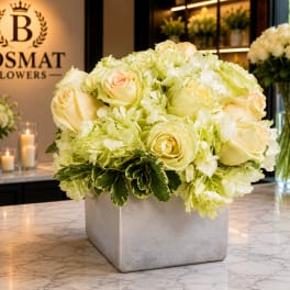 Cream roses and pale green hydrangeas in a square gray vase