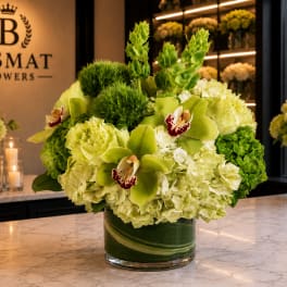Green hydrangea and orchid arrangement in a glass vase