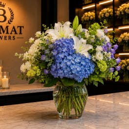 Blue hydrangeas and white lilies in a glass vase