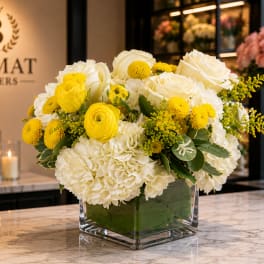 Yellow and white flower arrangement in a square glass vase