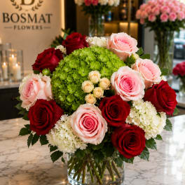 Bouquet of red and pink roses with white hydrangeas in a clear glass vase