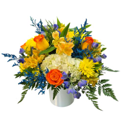 Bright mixed bouquet in a white vase with orange, yellow, blue, and purple flowers