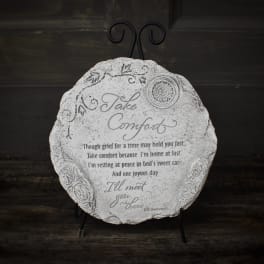 Round decorative plaque on a black stand with the words "Take Comfort"