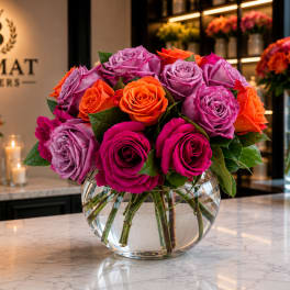 Bouquet of pink, purple, and orange roses in a clear glass vase
