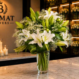 White lilies and green buds arranged in a clear glass vase