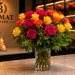 Bouquet of pink, yellow, and orange roses in a clear glass vase