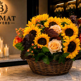 Basket arrangement of sunflowers and peach roses