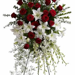Standing floral spray with red roses and white lilies on a black easel