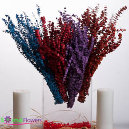 Tall multicolored floral arrangement in a clear vase with two white candles