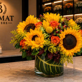 Sunflower and orange rose arrangement in a glass vase