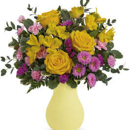 Yellow roses and pink flowers in a pale yellow vase