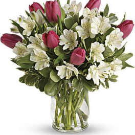 Pink tulips and white alstroemeria arranged in a clear glass vase