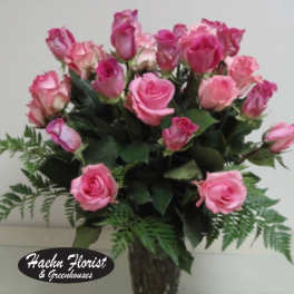 Pink roses arranged in a clear glass vase with fern accents.