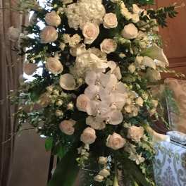 Tall white floral standing arrangement with roses, orchids, and calla lilies