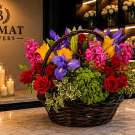 Basket arrangement of red roses, purple irises, and pink flowers