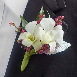White orchid boutonniere with pink filler flowers on a dark suit