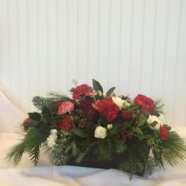 Holiday centerpiece with red and white carnations in a low rectangular container