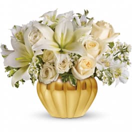 White lilies and roses arranged in a gold pumpkin-shaped vase