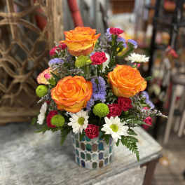 Bright mixed bouquet with orange roses in a mosaic vase