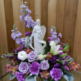Purple and white floral arrangement with an angel figurine
