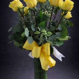 Yellow roses in a glass vase with a yellow ribbon