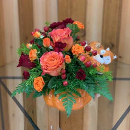 Orange and burgundy rose arrangement in a pumpkin-shaped container