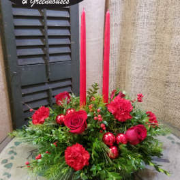 Red roses and carnations with tall red candles in a low arrangement