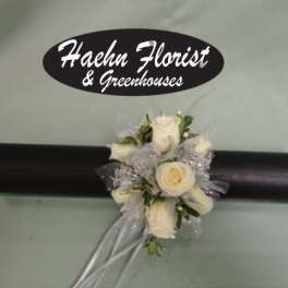 White rose corsage with silver ribbon on a black wristlet