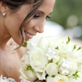 Bride holding a white bouquet of roses and small white flowers