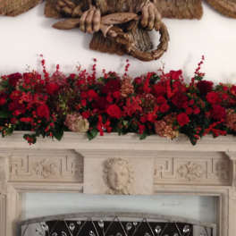 Long red floral arrangement displayed across a mantel