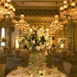Elegant banquet hall with tall white floral centerpieces and gold table settings