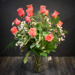Pink roses arranged in a clear glass vase with small white filler flowers
