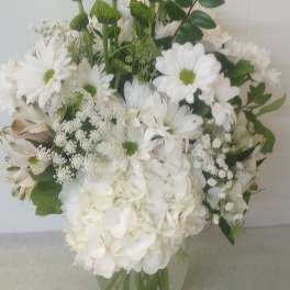 White bouquet with daisies, hydrangea, and green button mums in a glass vase