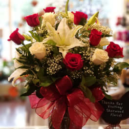 Bouquet of red and white roses with a white lily in a glass vase