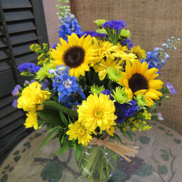 Yellow sunflowers and blue flowers in a glass vase