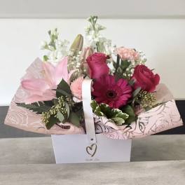 Pink and white mixed flower arrangement in a white box