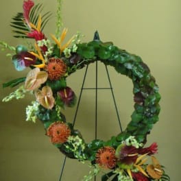 Tropical floral wreath with orange and red blooms on a black stand
