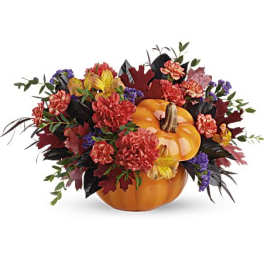 Pumpkin centerpiece with mixed fall flowers and leaves