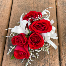 Small bouquet of red roses with white ribbon and tiny filler flowers