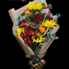 Bouquet of yellow sunflowers and red roses wrapped in brown paper