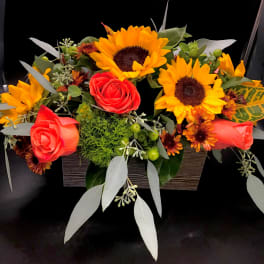 Arrangement of red roses and yellow sunflowers in a rectangular container