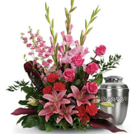 Pink lilies and roses arranged beside a silver urn