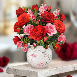 Bouquet of red and pink roses in a white painted vase