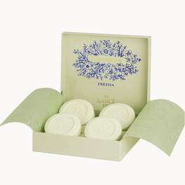 Open gift box with round white soaps and freesia branding