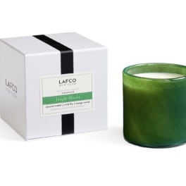 Green scented candle in a glass jar beside its white box