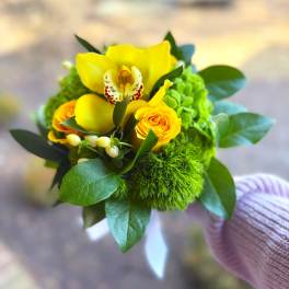 Small bouquet with yellow orchids and roses in a hand