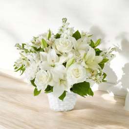 White lilies and roses arranged in a white basket