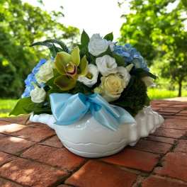Bouquet of white and blue flowers in a white ceramic bowl with a blue ribbon