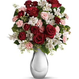 Red roses and pink carnations in a clear glass vase